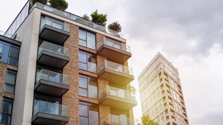 Modern apartments with spacious balconies and rooftop gardens under a cloudy sky.