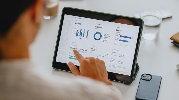 Close-up of business analyst reviewing financial data on tablet in office, demonstrating the use of technology in modern business environments.