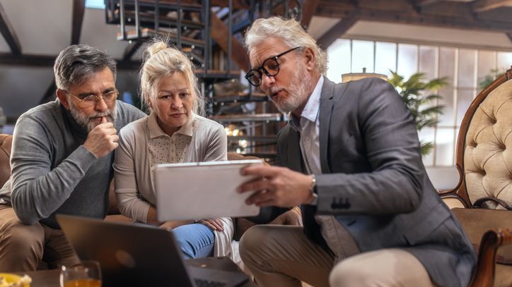 A senior couple meets with a financial advisor in their home.