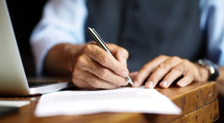 A close-up of a person signing paperwork.