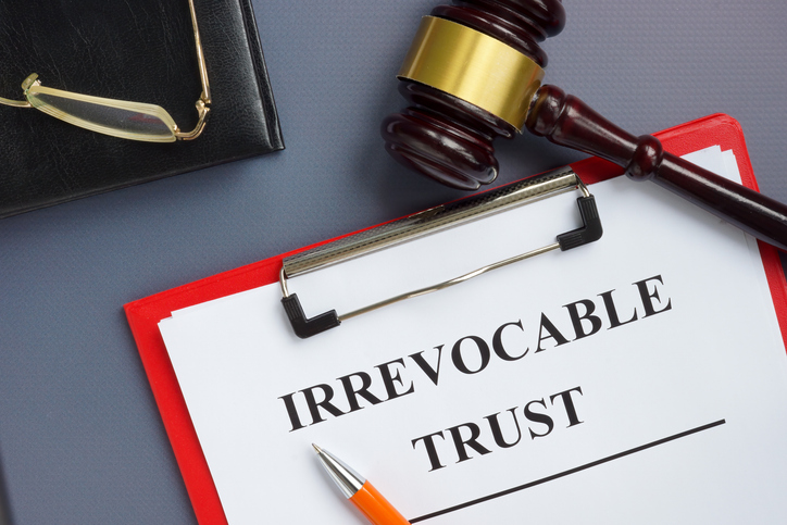 Closeup of a board with a gavel and a document for an irrevocable trust.