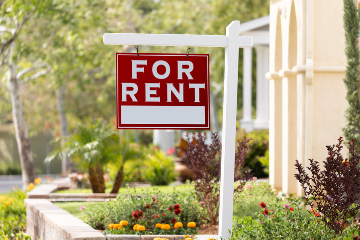 Closeup of a "For Rent" sign in front of a home.