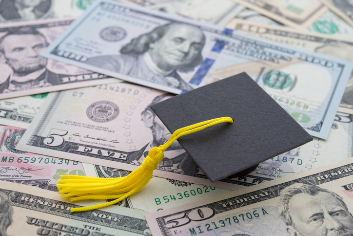 Closeup of a graduation cap resting on top of cash.