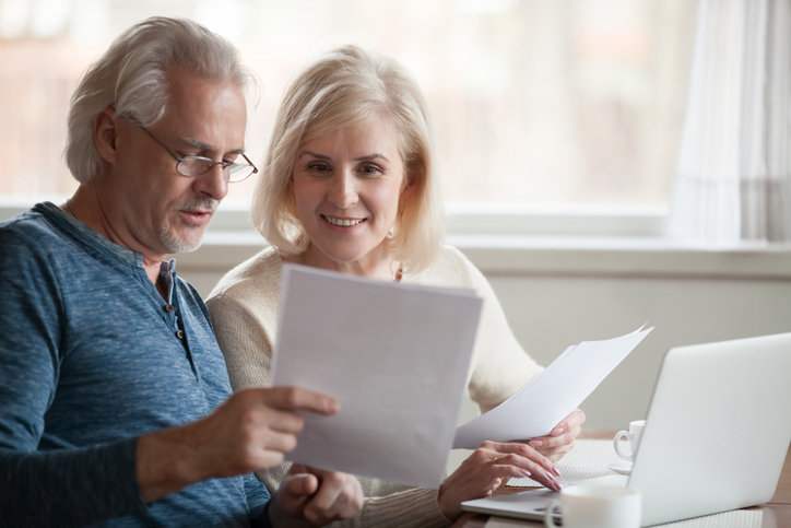 A middle-aged couple holding documents that break down their investment performance.