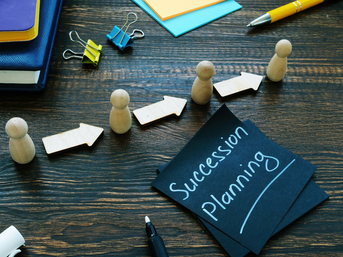 "Succession planning" written on a post-it note, along with wooden figurines and arrows.